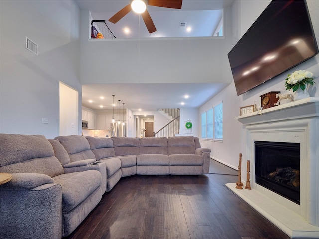 400 Beken Cove Ln, La Porte, TX 77571 - living room with a ceiling fan, a towering ceiling, dark wood finished floors, a fireplace with raised hearth, and stairway