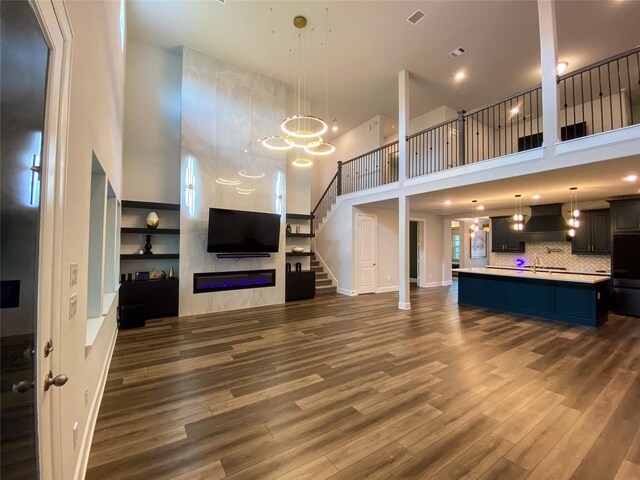 10011 Serenity Grove Dr, Missouri City, TX 77459 - unfurnished living room with a high ceiling, dark wood-style flooring, a chandelier, a large fireplace, and stairway