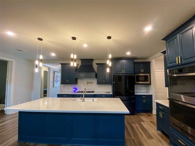 10011 Serenity Grove Dr, Missouri City, TX 77459 - kitchen with appliances with stainless steel finishes, custom range hood, decorative backsplash, dark wood finished floors, and a center island with sink