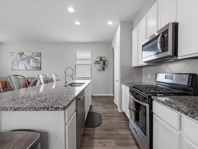 22010 Great Royal Ln, Houston, TX 77073 - kitchen featuring stainless steel appliances, a kitchen island with sink, dark stone countertops, white cabinetry, and recessed lighting
