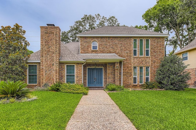 20746 Prince Creek Dr, Katy, TX 77450 - traditional-style house with a front yard, a chimney, roof with shingles, and brick siding