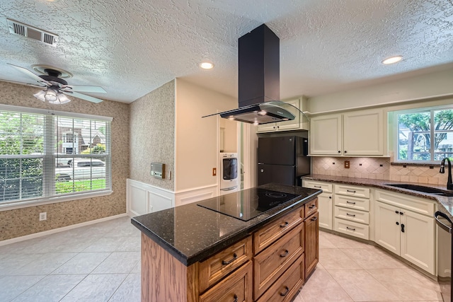 20746 Prince Creek Dr, Katy, TX 77450 - kitchen with wall chimney exhaust hood, black appliances, washer / dryer, a ceiling fan, and dark stone counters