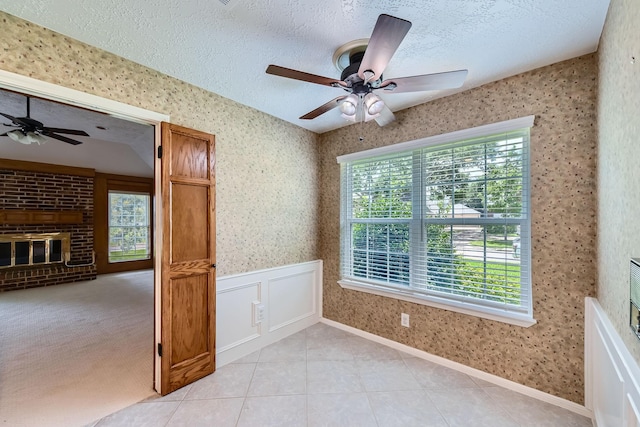 20746 Prince Creek Dr, Katy, TX 77450 - spare room featuring a ceiling fan, a textured ceiling, wallpapered walls, light tile patterned flooring, and a brick fireplace