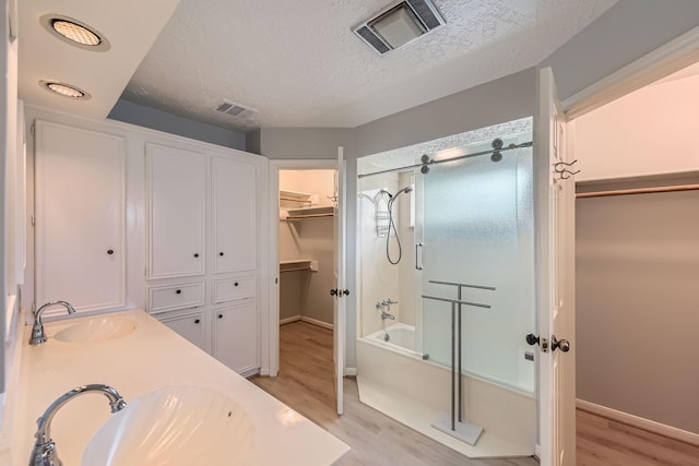 20746 Prince Creek Dr, Katy, TX 77450 - bathroom with wood finished floors, shower / bath combination with glass door, a textured ceiling, a spacious closet, and double vanity