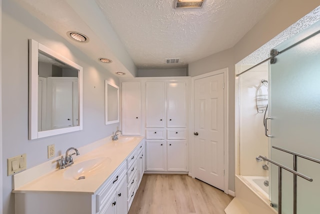 20746 Prince Creek Dr, Katy, TX 77450 - bathroom featuring wood finished floors, double vanity, a textured ceiling, and bath / shower combo with glass door