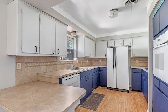 1015 Stevens Ave, Conroe, TX 77301 - kitchen featuring white appliances, a peninsula, tasteful backsplash, blue cabinetry, and light countertops