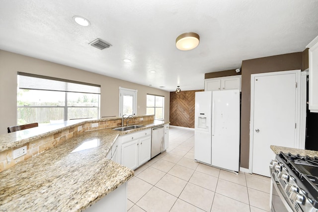 16227 Affirmed Way, Friendswood, TX 77546 - kitchen featuring stainless steel appliances, white cabinets, light stone counters, wood walls, and light tile patterned floors