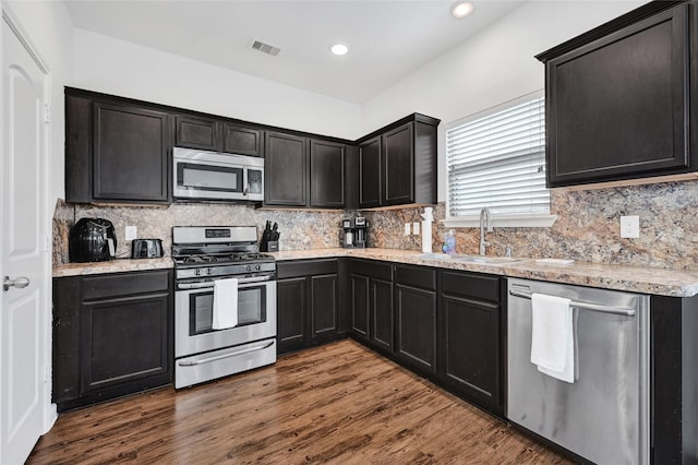 1611 Jaquima Valley Way, Houston, TX 77049 - kitchen featuring appliances with stainless steel finishes, decorative backsplash, dark wood-style floors, recessed lighting, and light stone countertops