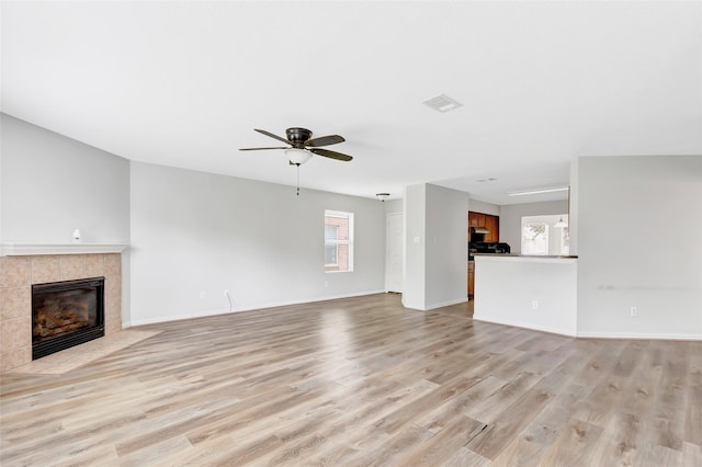 5019 Packard Elm Ct, Katy, TX 77449 - unfurnished living room with light wood-style flooring, a tiled fireplace, and ceiling fan