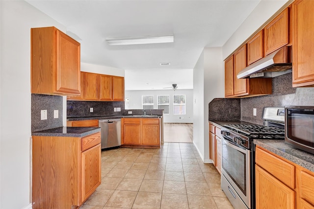 5019 Packard Elm Ct, Katy, TX 77449 - kitchen featuring appliances with stainless steel finishes, under cabinet range hood, a peninsula, light tile patterned flooring, and backsplash