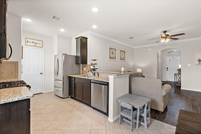 13203 Adolpho Dr, Houston, TX 77044 - kitchen with stainless steel appliances, dark brown cabinetry, ceiling fan, light stone counters, and crown molding