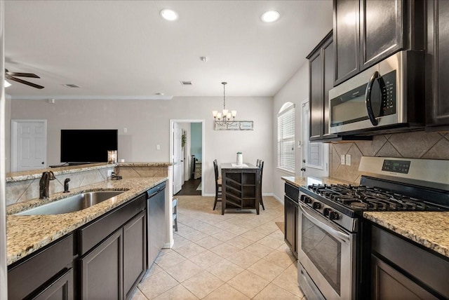 13203 Adolpho Dr, Houston, TX 77044 - kitchen featuring appliances with stainless steel finishes, a chandelier, tasteful backsplash, light tile patterned floors, and light stone countertops