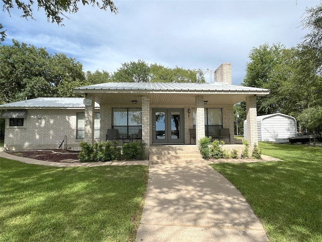 11391 Lakeshore Dr, Thornton, TX 76687 - view of front facade with covered porch, brick siding, a front lawn, a chimney, and a metal roof