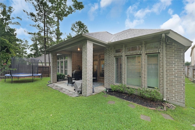 23649 Sage Villa Dr, New Caney, TX 77357 - back of house featuring a trampoline, a patio, brick siding, and roof with shingles