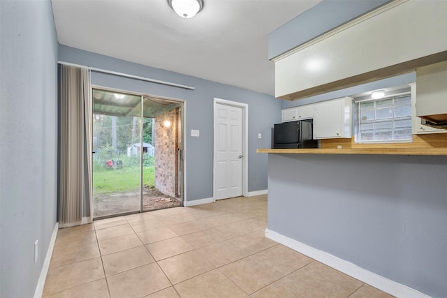 1204 Crescent Blvd, Cleveland, TX 77327 - kitchen with freestanding refrigerator, white cabinets, light tile patterned floors, and a peninsula
