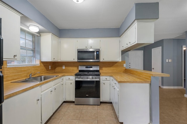 1204 Crescent Blvd, Cleveland, TX 77327 - kitchen with appliances with stainless steel finishes, light tile patterned floors, a peninsula, and decorative backsplash