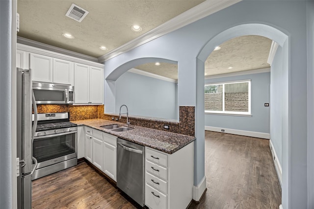 1773 Aden Dr, Houston, TX 77003 - kitchen with stainless steel appliances, crown molding, arched walkways, white cabinetry, and decorative backsplash