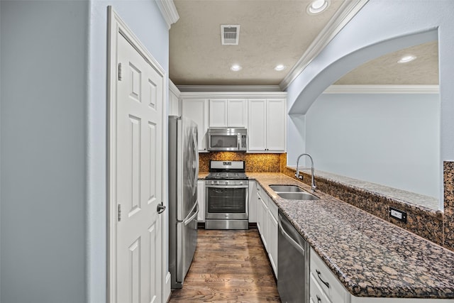 1773 Aden Dr, Houston, TX 77003 - kitchen with stainless steel appliances, crown molding, white cabinetry, dark stone countertops, and dark wood finished floors