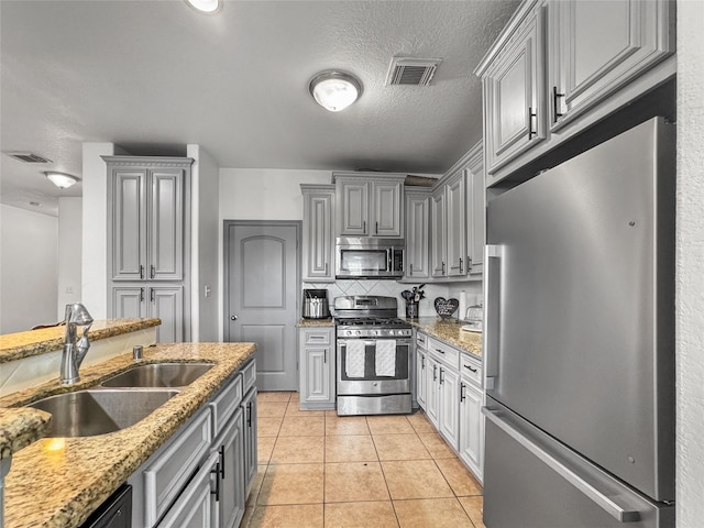 2905 Baer St Unit 6, Houston, TX 77020 - kitchen with stainless steel appliances, gray cabinetry, light stone counters, and a textured ceiling