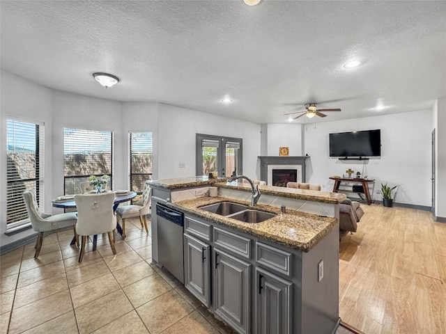 2905 Baer St Unit 6, Houston, TX 77020 - kitchen featuring dishwasher, ceiling fan, a glass covered fireplace, a center island with sink, and a textured ceiling