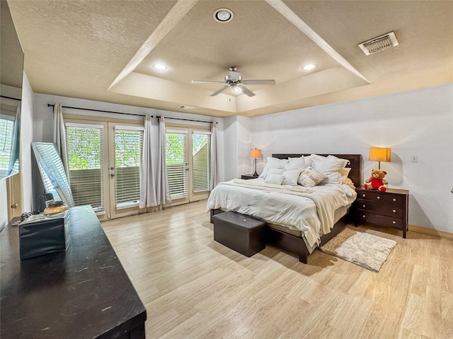 2905 Baer St Unit 6, Houston, TX 77020 - bedroom featuring a raised ceiling, access to outside, multiple windows, a textured ceiling, and wood finished floors