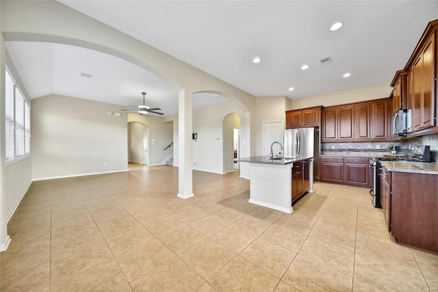 208 Harbor Bend Ln, Dickinson, TX 77539 - kitchen featuring appliances with stainless steel finishes, light tile patterned flooring, decorative backsplash, light stone counters, and a kitchen island with sink