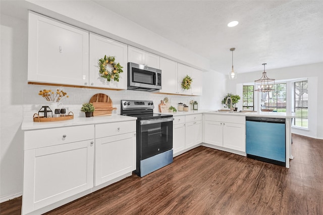 5518 Fair Forest Dr, Houston, TX 77088 - kitchen with stainless steel appliances, dark wood-style floors, a peninsula, tasteful backsplash, and a chandelier