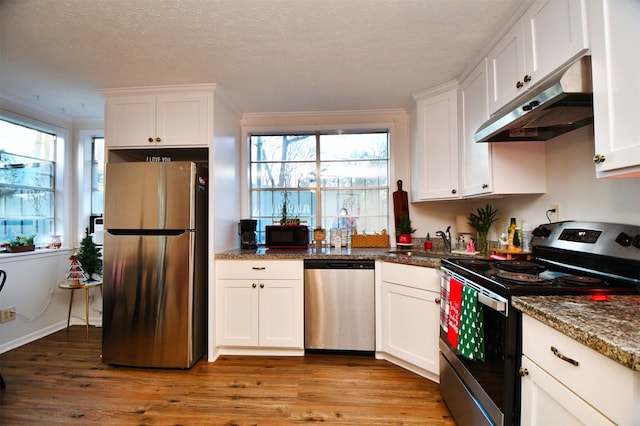 2019 N Thompson St, Conroe, TX 77301 - kitchen with appliances with stainless steel finishes, under cabinet range hood, healthy amount of natural light, white cabinets, and a textured ceiling
