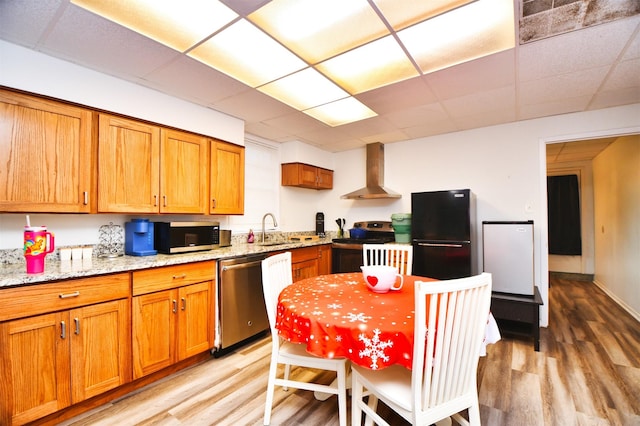 2019 N Thompson St, Conroe, TX 77301 - kitchen featuring stainless steel appliances, wall chimney range hood, light wood-style flooring, a paneled ceiling, and brown cabinets