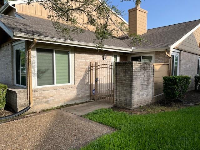 12117 Bob White Dr, Houston, TX 77035 - back of property featuring brick siding, a gate, and a chimney