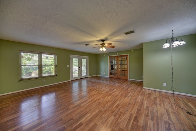 5425 Sandy Creek Ln, Brenham, TX 77833 - empty room featuring a textured ceiling, wood finished floors, a chandelier, a ceiling fan, and french doors