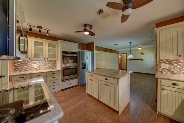 5425 Sandy Creek Ln, Brenham, TX 77833 - kitchen with a ceiling fan, appliances with stainless steel finishes, decorative backsplash, dark wood-style flooring, and glass insert cabinets
