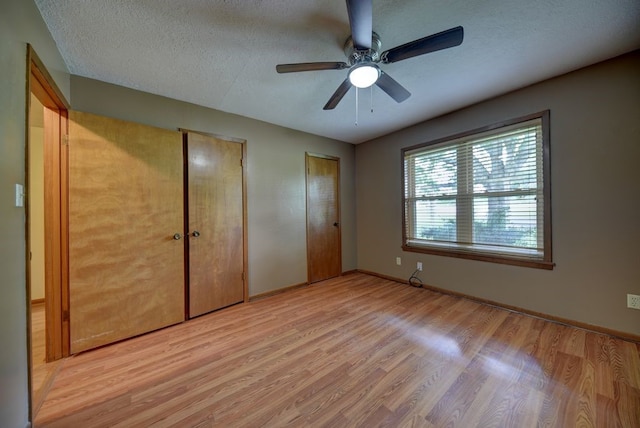 5425 Sandy Creek Ln, Brenham, TX 77833 - unfurnished bedroom featuring two closets, light wood-type flooring, a textured ceiling, and ceiling fan