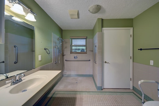 5425 Sandy Creek Ln, Brenham, TX 77833 - full bath featuring tile walls, a tile shower, a textured ceiling, tile patterned floors, and vanity