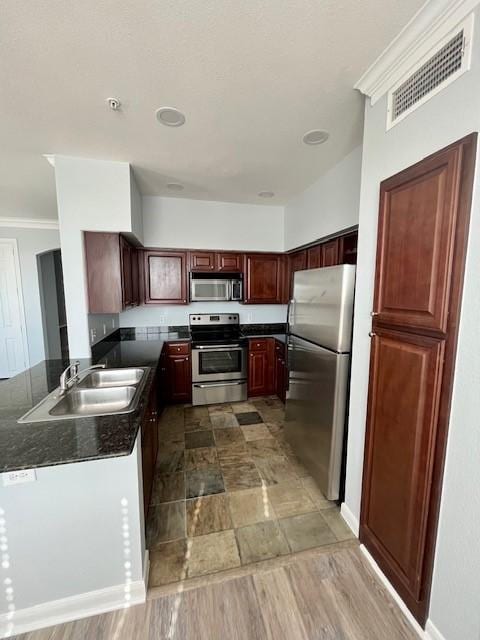 7575 Kirby Dr Unit 2314, Houston, TX 77030 - kitchen with appliances with stainless steel finishes, dark countertops, ornamental molding, a peninsula, and dark brown cabinets