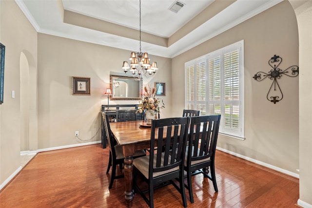 20811 S Amber Willow Trl, Cypress, TX 77433 - dining space featuring arched walkways, a chandelier, wood finished floors, a tray ceiling, and crown molding