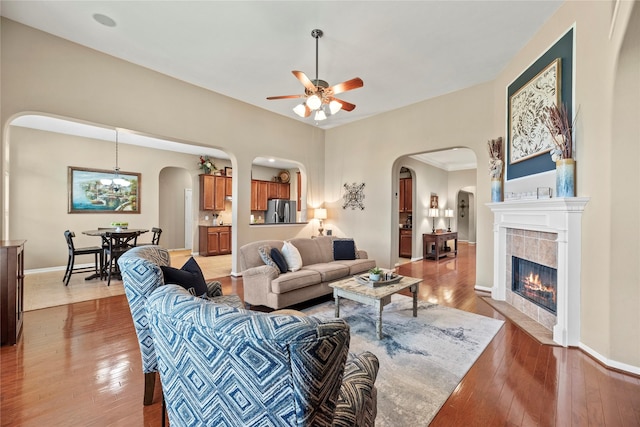 20811 S Amber Willow Trl, Cypress, TX 77433 - living room featuring arched walkways, a ceiling fan, light wood-style floors, and a tiled fireplace