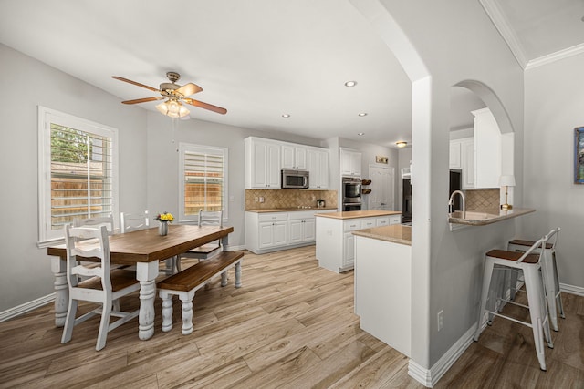 3506 Stanbury Place Ln, Katy, TX 77494 - kitchen with stainless steel appliances, a ceiling fan, light wood finished floors, a kitchen island, and recessed lighting
