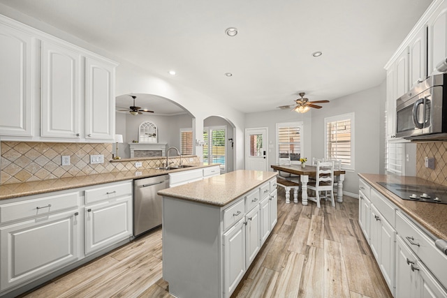 3506 Stanbury Place Ln, Katy, TX 77494 - kitchen featuring a ceiling fan, stainless steel appliances, a kitchen island, light wood-style floors, and white cabinetry