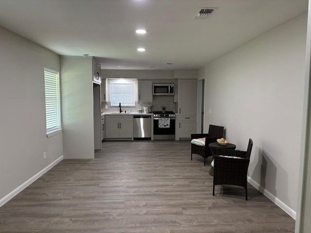 3706 Galway Ln, Houston, TX 77080 - kitchen featuring stainless steel appliances, wood finished floors, recessed lighting, tasteful backsplash, and light countertops