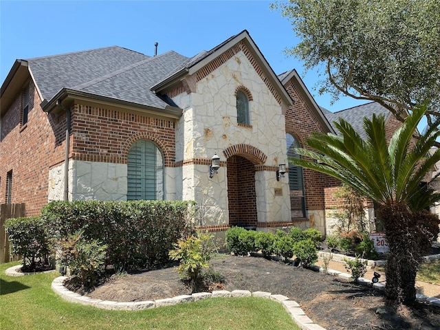 9711 Dill Canyon Ln, Katy, TX 77494 - french country style house featuring stone siding, a shingled roof, and brick siding
