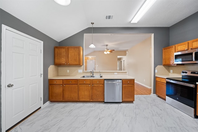 5532 N Buffalo Cir, Willis, TX 77378 - kitchen with appliances with stainless steel finishes, lofted ceiling, brown cabinetry, light countertops, and a peninsula