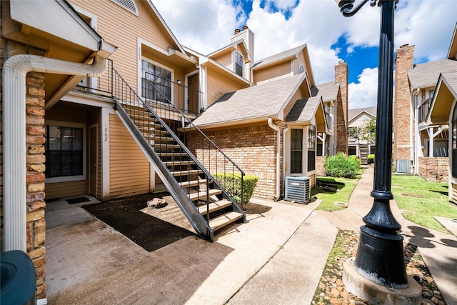 2300 Old Spanish Trl Unit 2063, Houston, TX 77054 - rear view of house featuring stairway, brick siding, a chimney, and a shingled roof
