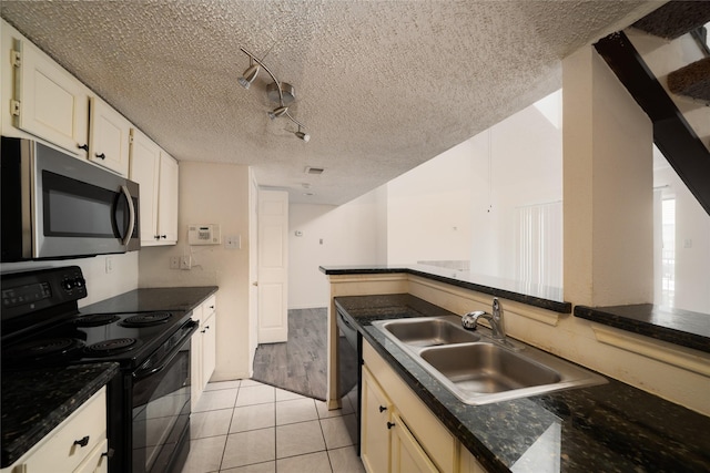 2300 Old Spanish Trl Unit 2063, Houston, TX 77054 - kitchen featuring black appliances, a textured ceiling, dark countertops, light tile patterned floors, and track lighting