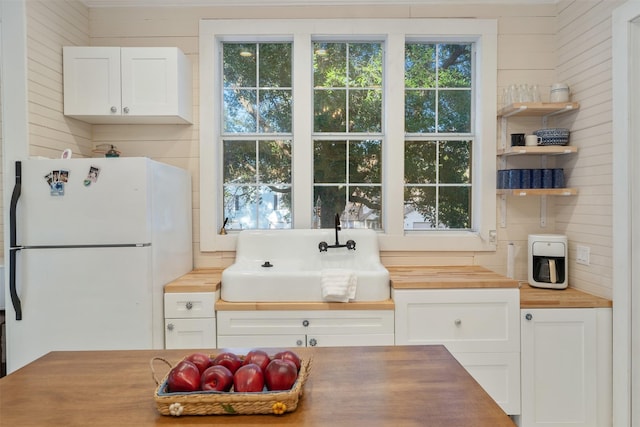 91 Willow St, Point Blank, TX 77364 - kitchen with freestanding refrigerator, butcher block counters, white cabinets, and healthy amount of natural light
