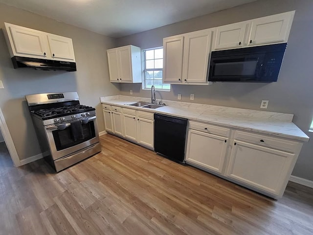 211 Peach St, Sweeny, TX 77480 - kitchen with black appliances, under cabinet range hood, light wood finished floors, white cabinets, and light stone counters