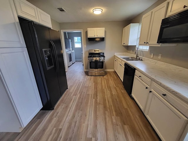 211 Peach St, Sweeny, TX 77480 - kitchen with black appliances, under cabinet range hood, white cabinets, light wood-type flooring, and healthy amount of natural light