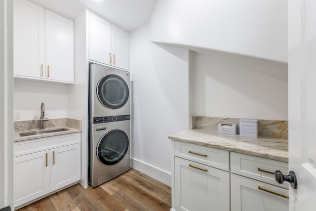 27706 Lakeway Trail Ln, Fulshear, TX 77441 - washroom with stacked washing machine and dryer, light wood-style flooring, cabinet space, and bar with sink