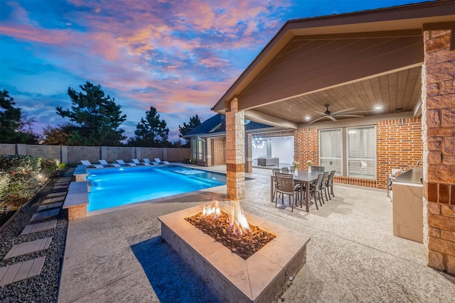 27706 Lakeway Trail Ln, Fulshear, TX 77441 - view of swimming pool featuring an outdoor fire pit, an outdoor kitchen, a patio area, outdoor dining space, and ceiling fan