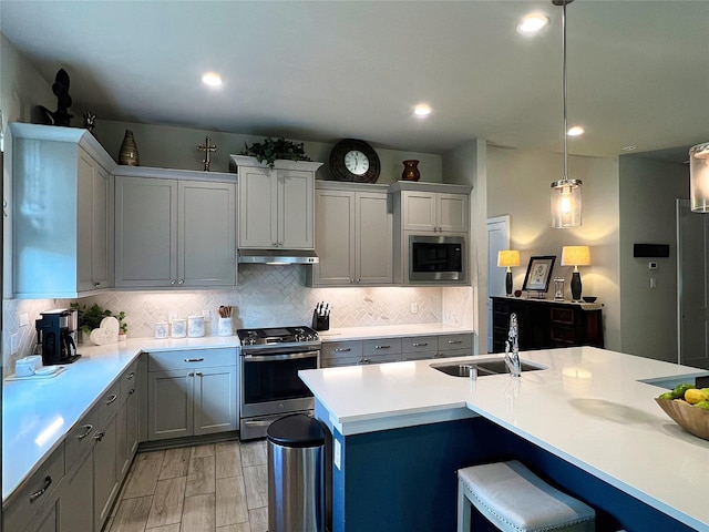 2 Ruchill Cir, Conroe, TX 77304 - kitchen with appliances with stainless steel finishes, under cabinet range hood, decorative backsplash, light countertops, and recessed lighting